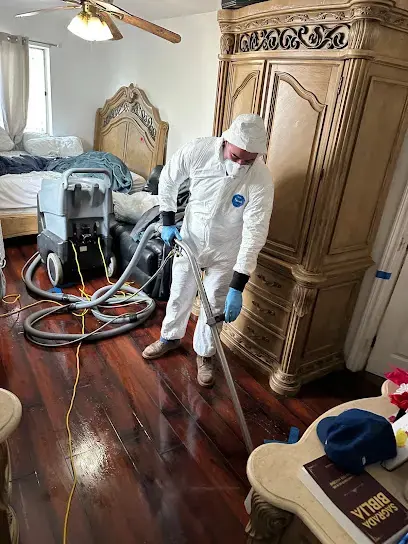 Technician in protective suit extracting water from a Lake Elsinore bedroom floor