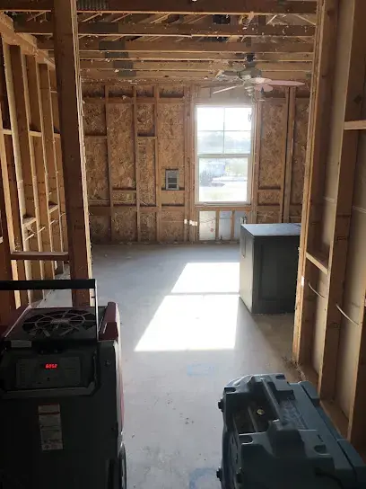 Dehumidifier running in a gutted Lake Elsinore room with the framing exposed to dry